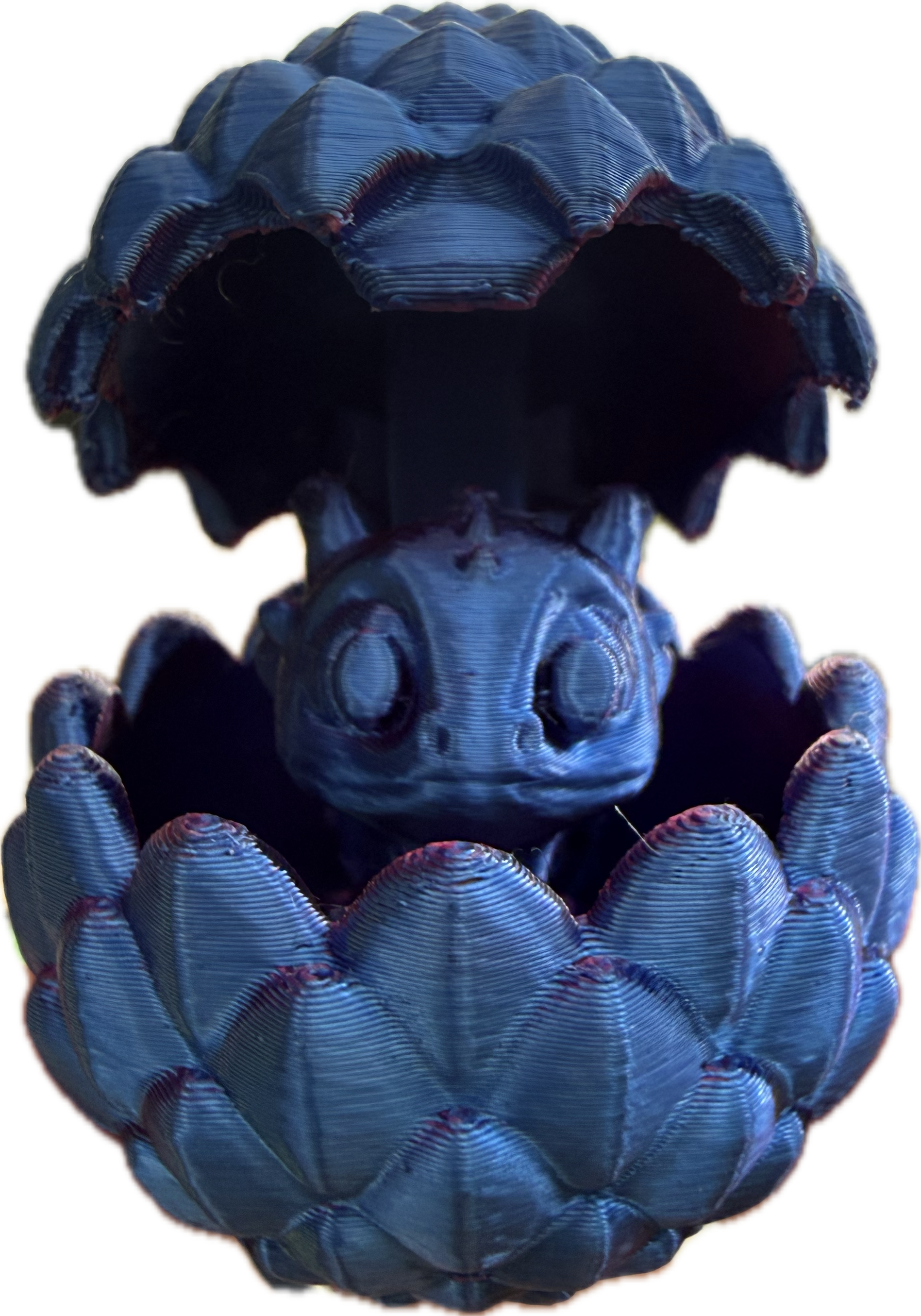 A small, blue figurine resembling a baby dragon with large eyes is nestled inside a scalloped shell.