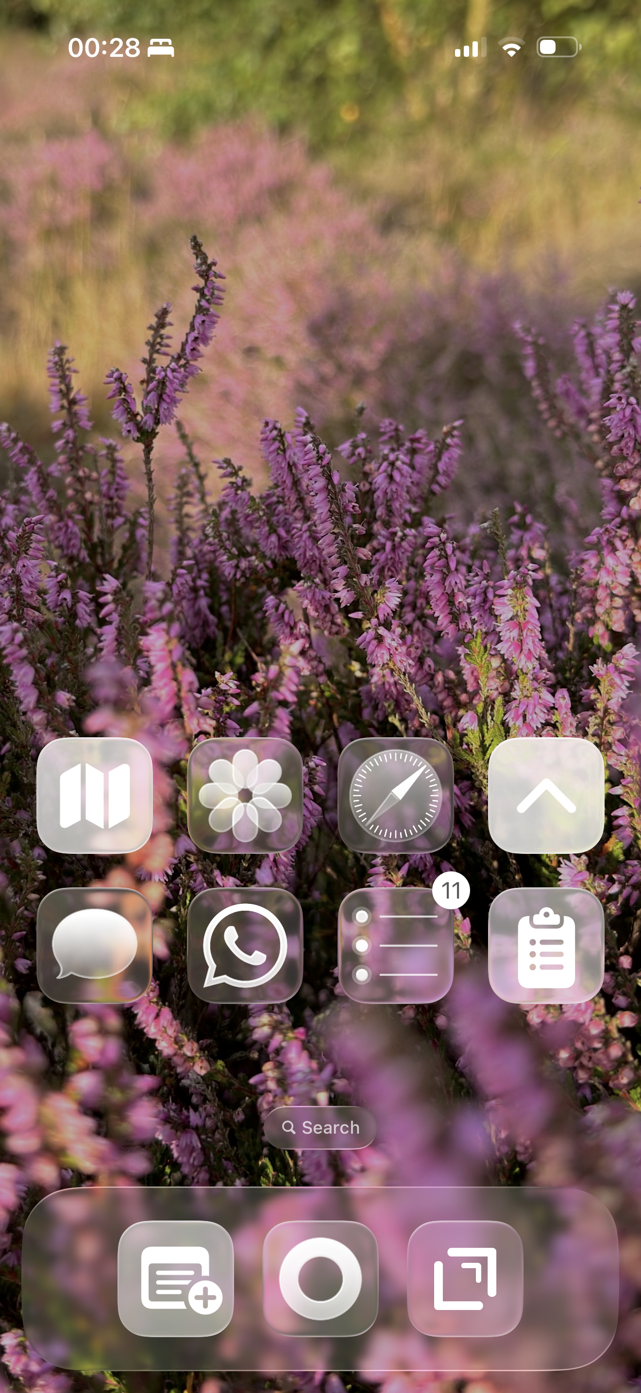 A smartphone home screen with translucent Liquid Glass icons is displayed over a blurred background of purple heather.