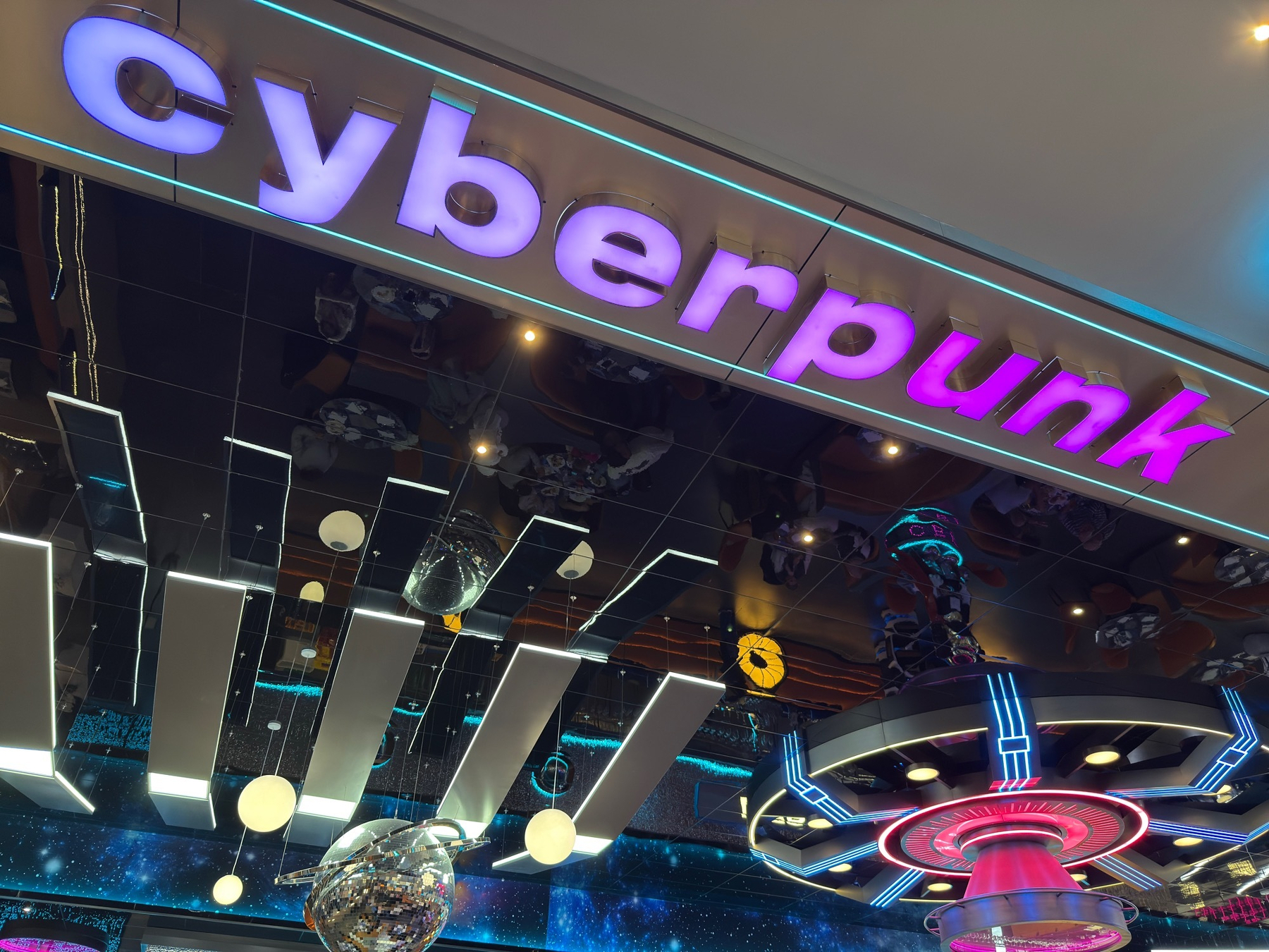 A futuristic scene featuring glowing lights and the word cyberpunk illuminated on a ceiling display.